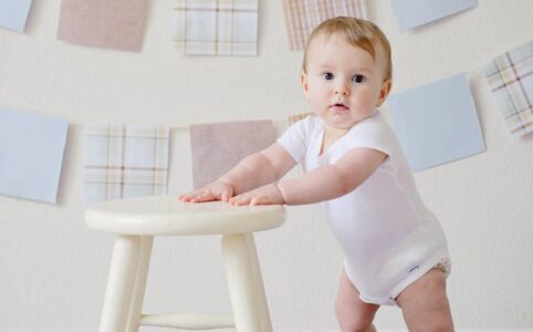 baby holding white wooden stool