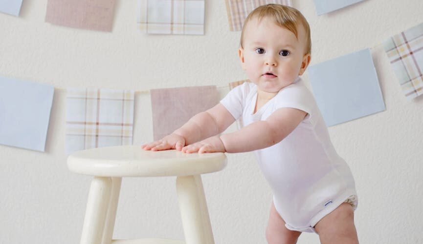 baby holding white wooden stool