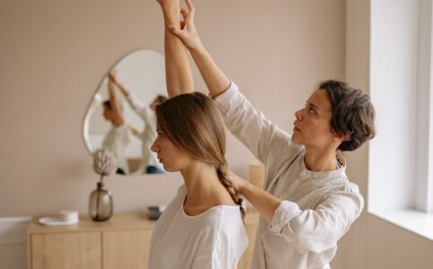 woman in white shirt sitting on white bed while raising her right hand