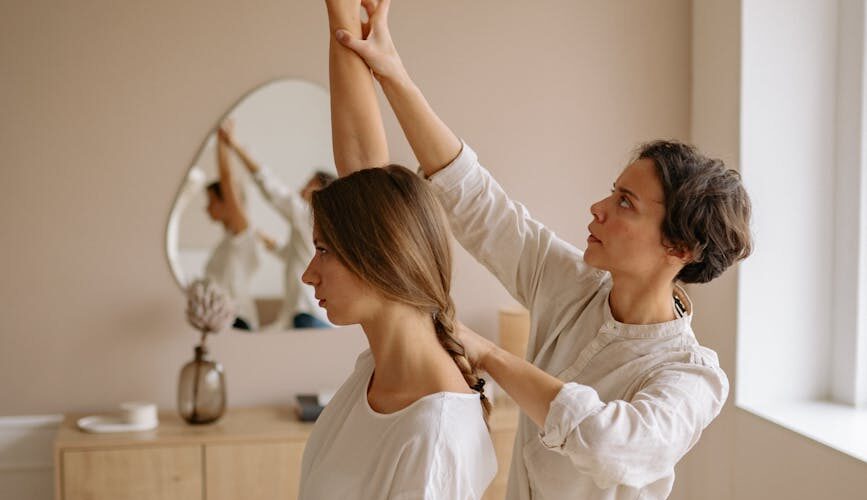 woman in white shirt sitting on white bed while raising her right hand