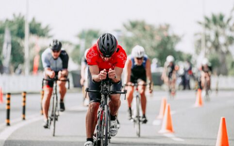 unrecognizable cyclists riding bikes on road during race