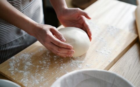 hands holding dough on cutting board