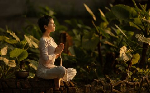 woman meditating in a garden at dawn